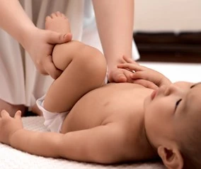 A baby lying on its back, being massaged. 