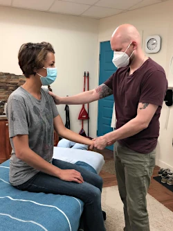 Client receiving instruction from masked therapist