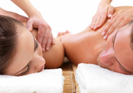 A couple lying on side-by-side massage tables