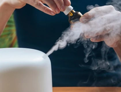 An essential oil bottle being held near a diffuser