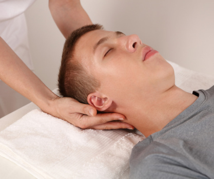 Man receiving craniosacral therapy while lying on back