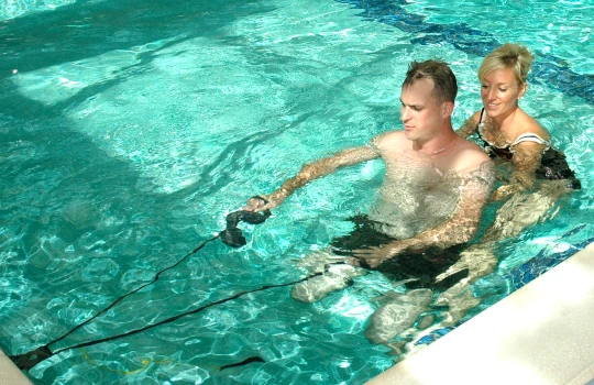 An occupational therapists assists a marine in a pool.