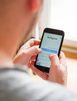 Over-the-shoulder view of a person using Instagram on their smartphone. 