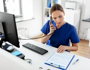 A practitioner on the phone consulting a clipboard