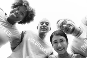 Four people in a huddle looking towards camera and wearing volunteer shirts.