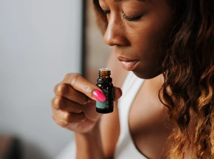 A woman inhaling from an essential oil bottle