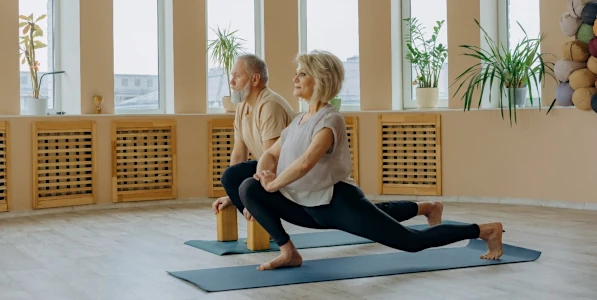 Two yoga practitioners in a forward lunge pose. 